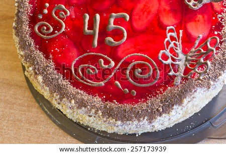 Tasty cake with number forty-five on a wooden background