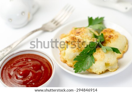 Delicious cauliflower fried in egg with herbs and tomato sauce and a fork