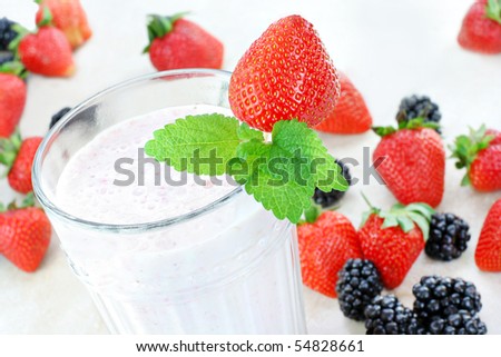 Delicious and fresh berry smoothie top view.  Strawberries and blackberries surround the glass.