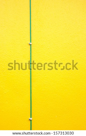 Green electrical ground wire on yellow wall