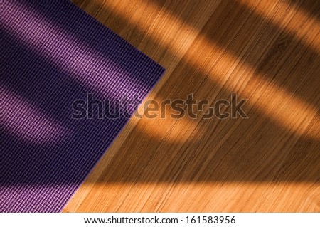 yoga mat on wooden floor in evening light with shadows from window
