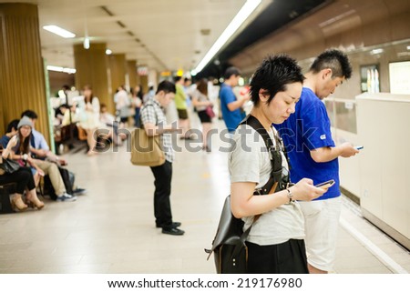FUKUOKA,JAPAN - July 26, 2014 : Japanese people are using mobile phones while waiting in the subway of Fukuoka,Japan on July 26, 2014.