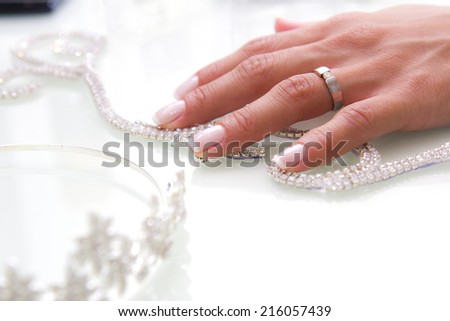 Bride hand with ring and jewelery on the  white  table.