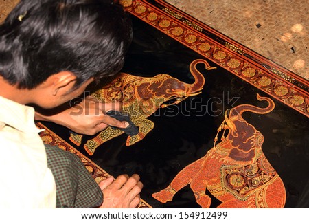 BAGAN, MYANMAR - FEBRUARY 15, 2013: A man is working on an extremely fine piece of lacquer ware. Lacquer ware is a specialty of Bagan, and is sold worlwide for high prices.