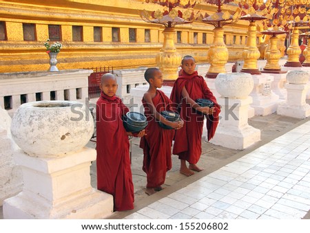 BAGAN, MYANMAR - FEBRUARY 16, 2013: Three young buddhist monks are standing in the famous Shwezigon Pagoda, Bagan, collecting money.