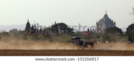 A horse-drawn carriage is driving along in front of the famous ancient That Byin Nyu Temple of Bagan. Bagan is a historic royal city in Myanmar with over two thousand preserved pagodas.