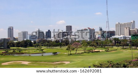 In the center of Bangkok, in the middle of the commercial district, is a golf course. It is surrounded by the towers and skyscrapers of the city.