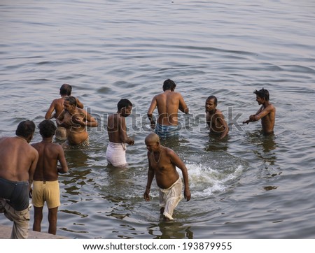 VARANASI, INDIA - FEBRUARY 20, 2014: a group of men is taking a holy bath in the river Ganges