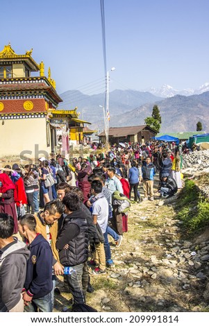 TASHIDING, INDIA - MARCH 16, 2014: At the bumchu festival, Tashiding, Sikkim, Buddhist believers, men and women, are queuing in two lines to get into the temple. In the background is the himalaya.
