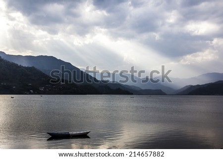 Dark clouds obscure the sun over Pokhara lake. A big ray of sun finds it\'s way through the clouds.