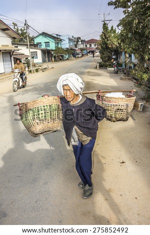 KENG TUNG, MYANMAR - JANUARY 28, 2015: A street seller in Myanmar is caying her goods in baskets