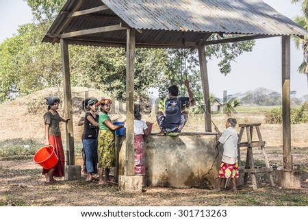 MAWLAMYINE. MYANMAR - FEBRUARY 11, 2015: Women are waiting at a rural well while the boys are pulling up the water, on the so called island of ogre at Mawlamyine, Myanmar.