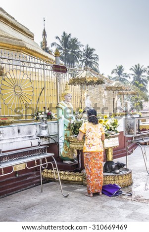 DAWEI, MYANMAR - FEBRUARY 16, 2015: A buddhist believer is worshipping the Buddha at the beautiful golden pagoda of Dawei in the south of Myanmar.