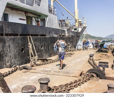 MYEIK, MYANMAR - FEBRUARY 23, 2015: Porters are carrying the cargo from a ship fastened to one of the jetties in the harbor of Myeik in the south of Myanmar.