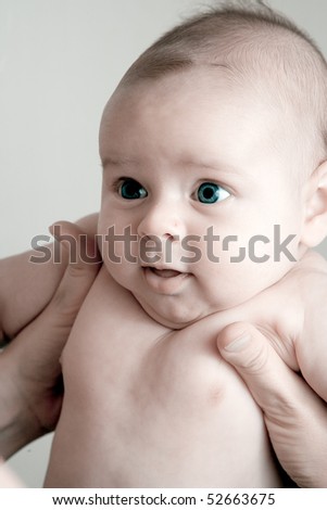 Newborn baby being held looking very cute with blue eyes