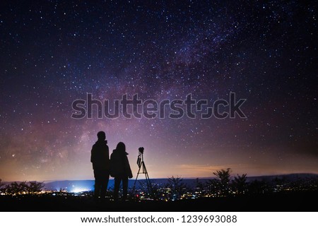 Silhouettes of people observing stars during night and taking photo of starry sky. Astronomy and Astrophotography concept.