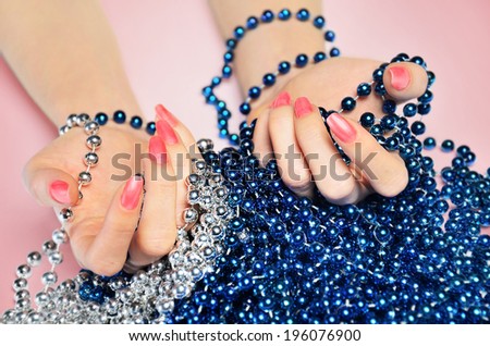 Hand with beads on pink table