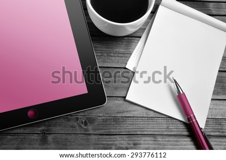 Tablet empty pink screen with notepad on desk