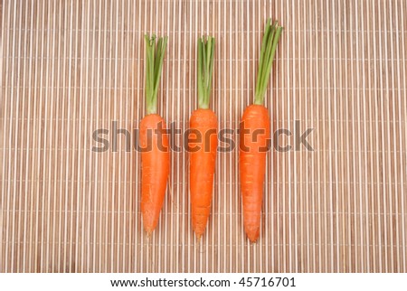 Three carrots isolated on a bamboo mat