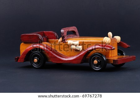 A toy car made of wood on black