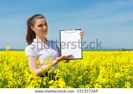 business woman with yellow flowers and blank sheet on field