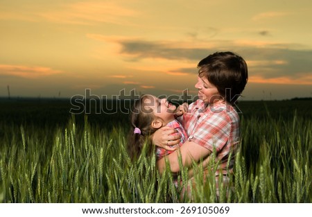 happy mother and child in green field at sunset