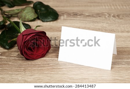 Red rose flower with nlank paper on wood
