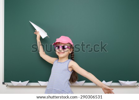 Schoolgirl with origami plane near school board