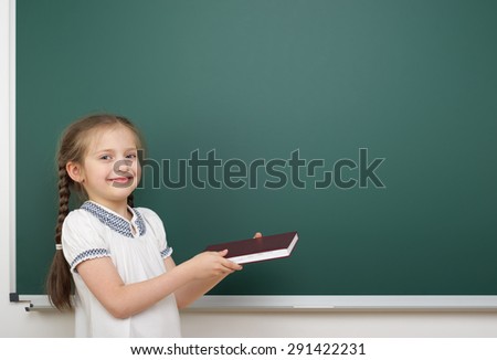 Schoolgirl with book near the school board