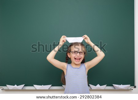 Schoolgirl with origami ship near the school board