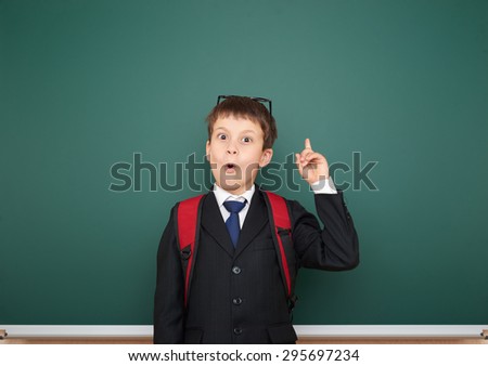 Schoolboy with backpack on school board background