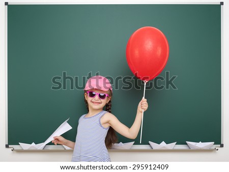 Schoolgirl with red balloon near the school board