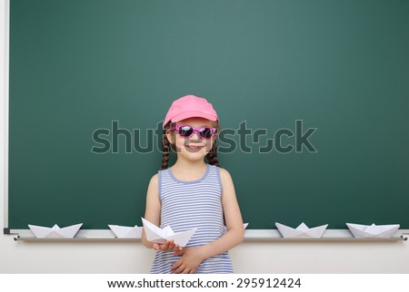 Schoolgirl with origami ship near the school board