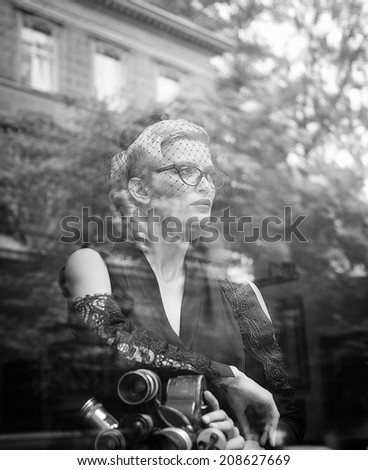 Elegant blond retro woman in black dress with camera
