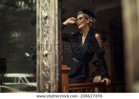 Elegant blond retro woman in black dress with camera