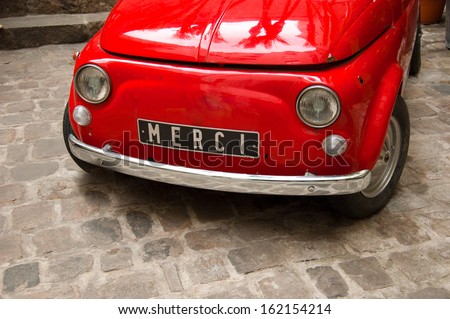 Old vintage Italian car in red with Merci written on the plate