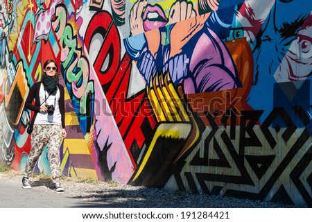BROOKLYN, NYC, US, October 1 2013: Street art in Brooklyn. Hipster female photographer walking next to a wall of graffiti in Brooklyn, New York, US.