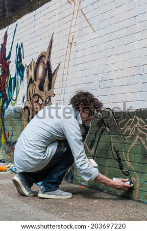 SHOREDITCH, LONDON, UK, June 8 2014: Street art in Shoreditch. Urban artist drawing graffiti on a wall in Shoreditch.