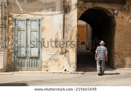 Old Italian man walking along ancient medieval lanes  in the city of Marsala, Sicily, Italy.