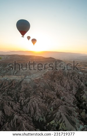 Three hot air balloons over a desert landscape in the Turkish region of Cappadocia at sunrise. Turkey.