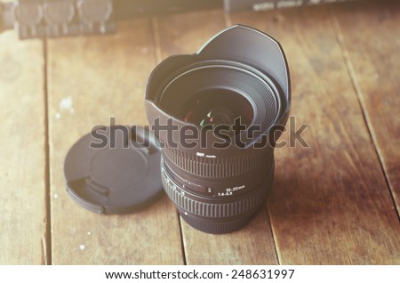 Camera lens on wood background with vintage filter