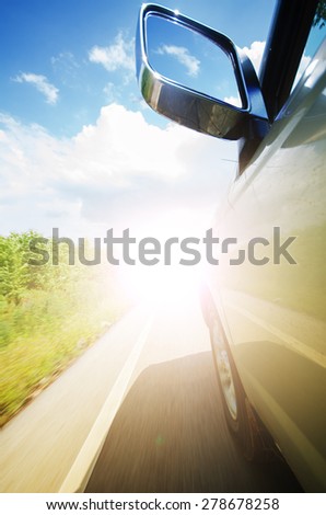 Rear view mirror of car on the road with motion and light background.