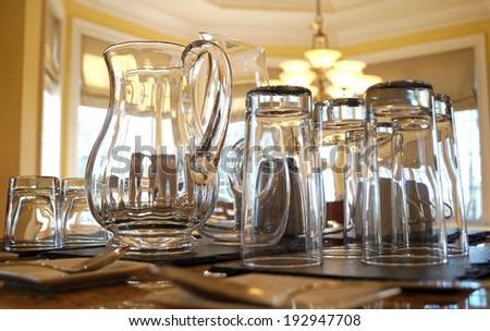 Water Pitcher and Glasses.  Glass water pitcher and drinking glasses on a table in the kitchen.