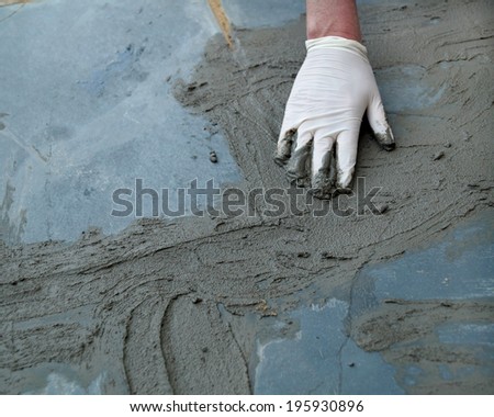 Home Improvement Project.  A man working on a home improvement project repairs a cracked sidewalk with wet cement.