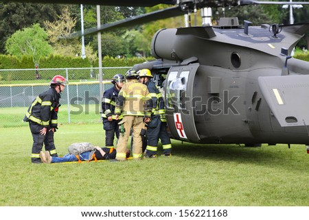 Eugene, Oregon, USA Â?Â? May 2, 2012: Eugene, OR Emergency Services and National Guard work in a disaster response drill. Unidentified firemen carried injured person and discussing the best way to load.