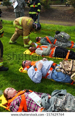 Eugene, Oregon Usa Â?Â? May 2, 2012: Eugene, Or The Local Emergency Services And National Guard Work Together In A Disaster Drill. The Firemen Are Reviewing The Injury Status Cards On The Injured.
