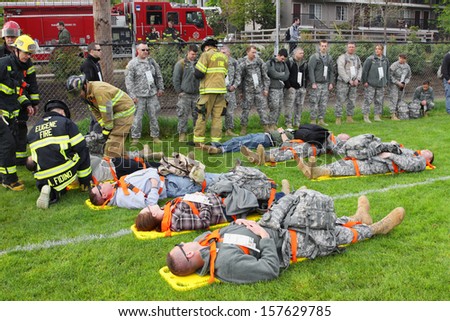 EUGENE, OREGON, USA  May 2, 2012: Eugene, OR the local Emergency Services and National Guard work together in a disaster drill. The firemen are reviewing the injury status cards on the injured.