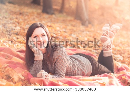 Young beautiful woman lying on a rug in an autumn park and wearing knitted sweater socks and gloves