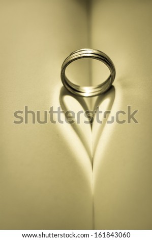 Ring and heart shaped shadow over a Bible