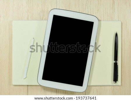 digital tablet with notepad and pen on wooden tablet.